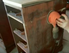 a person using a sander on a wooden cabinet