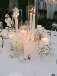 a table topped with lots of white flowers and candles