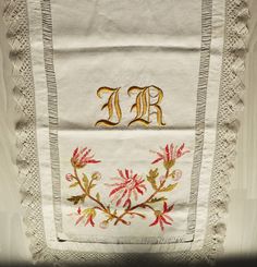 an embroidered handkerchief with the letter e on it, and flowers in gold embroiderys