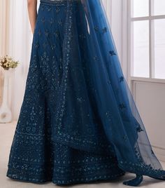 COLOR : Teal Blue FABRIC : Top (Blouse) - Soft Net, Bottom (Lehenga) - Soft Net, Dupatta - Soft Net WORK : Dori, Zarkan, Sequins OCCASION : Wedding, Reception, Mehendi, Engagement READY-TO-WEAR : NoSTITCHING : Available as semi-stitched fabric, can be stitched using standard size option (+$30). Note: There might be a slight color variation due to lighting and flash used during photoshoot. The bright shade seen is the best closer view of fabric's color. Blue Floor-length Gown For Eid, Blue Gown With Intricate Embroidery For Eid, Designer Blue Gown With Intricate Embroidery, Blue Gown With Intricate Embroidery For Designer Wear, Blue Fitted Sharara With Intricate Embroidery, Blue Floor-length Dress With Dupatta, Blue Semi-stitched Dress For Wedding, Blue Dress With Resham Embroidery For Wedding, Blue Wedding Dress With Resham Embroidery