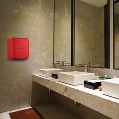 a bathroom with two sinks and a red soap dispenser on the wall