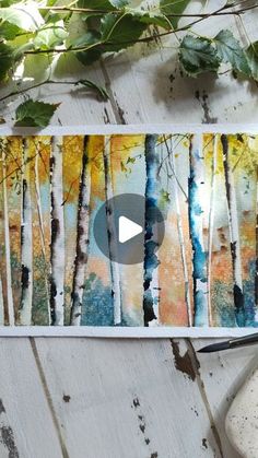 an art project with watercolors and paint on paper, including trees in the background