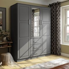 a bedroom with a large gray armoire next to a window and a rug on the floor