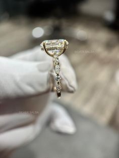 a close up of a person's hand holding a ring with diamonds on it