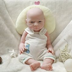 a baby doll sitting on top of a white blanket