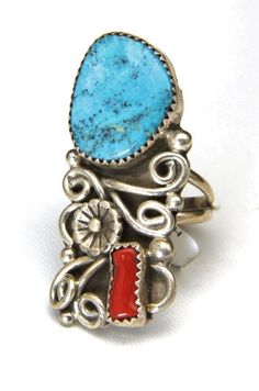 Handmade Navajo Turquoise and Coral Ring!-Artisan Kenneth Jones beautifully made ring-Large bright blue turquoise stone and deep red coral piece adorn this ring-Intricate silver work with curls, small bubbles, and a pretty central flower-Ring is marked "Sterling" "K", sticker tag states artist name and ring information-Ring face measures 1.7" x .75"-Turquoise stone measures about 18mm x 15mm, coral stone measures 10mm x 4mm-Depth of ring .23"-Size 7.5-Total weight 10.6g-Ring is in excellent cond Collectible Blue Multi-stone Turquoise Ring, Collectible Multi-stone Blue Turquoise Ring, Unique Blue Turquoise Multi-stone Ring, Unique Blue Turquoise Ring With Inlay, Bohemian Untreated Blue Turquoise Ring, Southwestern Multi-stone Turquoise Ring, Southwestern Blue Jewelry With Large Stone, Southwestern Style Blue Turquoise Ring With Natural Stones, Southwestern Blue Turquoise Ring With Natural Stones