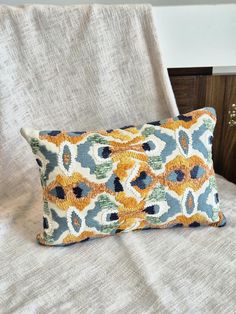 an orange and blue pillow sitting on top of a bed