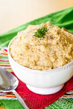 a white bowl filled with oatmeal sitting on top of a red and green place mat