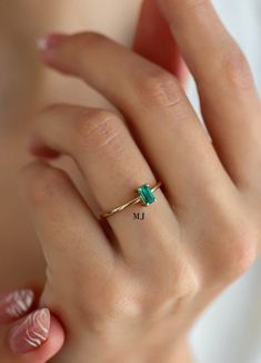 a woman's hand with a ring on it and a green stone in the middle