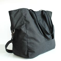 "Black 2 Way Waxed Canvas Tote MATERIALS Exterior fabric: 100% black waxed cotton canvas (British) Lining fabric: 100% cotton twill (Italian) APPROXIMATE DIMENSIONS Width: 35.5cm / 14\" Depth: 17cm / 6.75\" Height: 36cm / 14\" Shoulder strap length: adjustable from 75cm to 136cm / 29.5\" to 53.5\" Interior zipper pocket: 25cm / 10\" W x 21.5cm /8.5\" H Interior sleeve pocket 1: 9cm /3.5\" W x 15cm / 6\" H x 2cm / 0.75\" D Interior sleeve pocket 2: 8cm /3.25\" W x 15cm / 6\" H x 2cm / 0.75\" D DE Black Canvas Duffle Bag, Black Canvas Duffle Bag Tote, Black Canvas Tote Duffle Bag, Black Duffle Bag With Pockets For On-the-go, Black Canvas Weekender Bag For Everyday, Everyday Black Tote Duffle Bag, Black Waxed Canvas Duffle Bag For Travel, Black Waxed Canvas Travel Duffle Bag, Black Duffle Bag With Pockets For Everyday Use