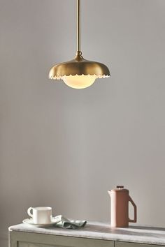 a light hanging over a table next to a cup and saucer on the counter