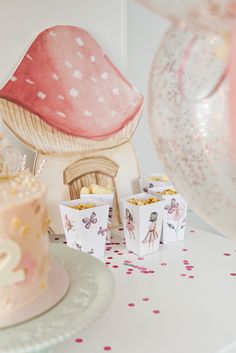 a table topped with a pink cake and cupcakes