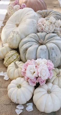 a bunch of white pumpkins sitting on top of a table next to some flowers