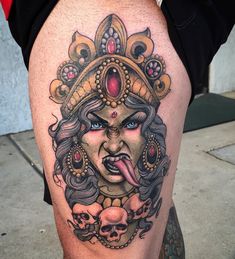 a woman's thigh with an evil face and skulls on the side, as well as her tongue