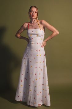 The designer Estefanía Álvarez's mastery in balancing modern shapes with romantic femininity is evident in the Rainbow Cherry Tomato dress. Crafted with lightweight and lustrous linen, this elegant and cheerful dress is detailed with an embroidery of flowers and cherry tomatoes, adorned with a delicate multicolored bias ribbon that enhances the back. Pair it with a simple pair of low-heeled sandals and an open back for a bold yet sophisticated look. Fitted Embroidered Summer Dress For Brunch, Fitted Embroidered Dress For Summer Brunch, Fitted Floral Embellished Maxi Dress For Summer, Summer Dress With Floral Embroidery And Fitted Bodice, Fitted Bodice Floral Embroidery Summer Dress, Fitted Linen Embroidered Summer Dress, Fitted Linen Dress With Floral Print, Summer Linen Embroidered Dress For Garden Party, Summer Embroidered Linen Dress For Garden Party