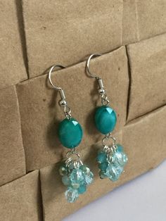 the earrings are made with glass beads and silver wire, on top of a cardboard box