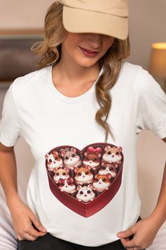 Step into a world of cuteness with our unique Cartoon Hamster Heart Box T-Shirt! Crafted from premium soft cotton, this shirt provides comfort that lasts all day long. The delightful graphic featuring cartoon hamsters nestled in a heart-shaped box is sure to capture hearts and spark conversations. This tee is a perfect blend of style and playfulness, making it an ideal gift for pet lovers of all ages. Suitable for both kids and adults, it comes in a range of sizes to ensure the perfect fit. Whet Character Print Crew Neck Top As Gift, Crew Neck Top With Character Print As Gift, Casual Tops With Character Print For Gifts, White T-shirt With Heart Graphic As Gift, Graphic Tee With Character Print As Gift, Playful Graphic Print Tops As Gift, Graphic Tee T-shirt With Character Print For Gift, Short Sleeve Cartoon Print Top As Gift, Kawaii Short Sleeve Tops For Gift