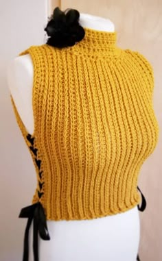 a mannequin wearing a yellow knitted sweater with a black flower on it