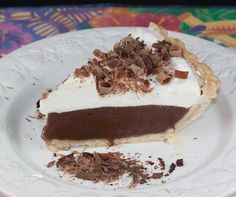 a piece of pie on a plate with chocolate shavings and whipped cream topping