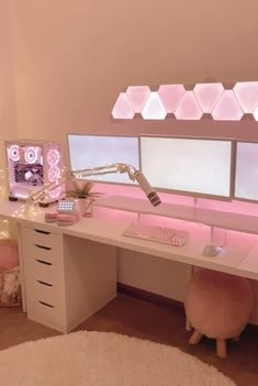 a white desk topped with two monitors next to a window covered in fairy light garlands