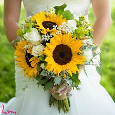 a bride holding a bouquet of sunflowers and greenery