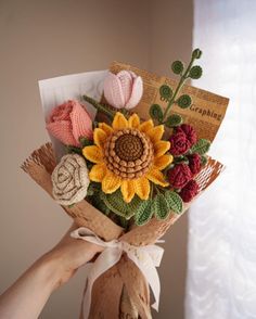 a person holding a bouquet of crocheted flowers