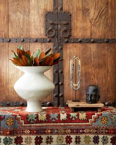 a vase filled with flowers sitting on top of a table next to a wooden door