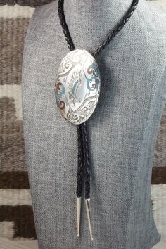 This turquoise & coral chip inlay, and sterling silver bolo tie features an eagle and was made by Navajo silversmith Raymond Begay. The back of the bolo tie is signed Ray B and stamped sterling.Tie Length: 23"Length: 3"Width: 2 1/8"Tips:Length: 1 5/8"Width: 1/4"Free shipping on all orders! We ship with USPS and always include tracking. All orders ship within a day of payment.Returns are accepted up to 30 days after you receive your order. Just send us a message. Our shop offers cash back or stor Artisan Lariat Jewelry For Rodeo, Western Style Hand Tooled Bolo Ties As Gift, Artisan Hand-tooled Jewelry For Rodeo, Hand Tooled Western Bolo Ties As Gift, Western Style Concho Jewelry For Shows, Southwestern Lariat Bolo Tie For Rodeo, Southwestern Concho Bolo Tie As Gift, Traditional Adjustable Jewelry For Rodeo, Southwestern Hand-tooled Jewelry For Ranch