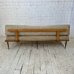 a wooden bench sitting on top of a hard wood floor next to a brick wall