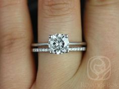 a woman's hand with a diamond ring on top of her finger and the engagement band