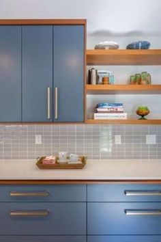 a kitchen with blue cupboards and white counter tops in front of bookshelves