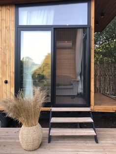 a wooden deck with a chair next to it and a glass door on the side