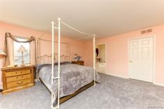 a bedroom with pink walls and carpeted flooring