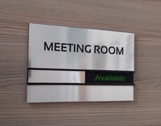 a metal sign mounted to the side of a wooden wall that says meeting room available