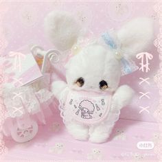 a white teddy bear with a pink bib