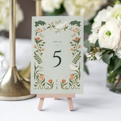 the table numbers are displayed on wooden easers with flowers in vases behind them