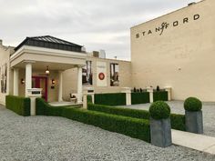 the front entrance to stanford college with topiary trimmed in boxwood and stone pillars