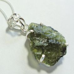 Moldavite crystal pendant in sterling with genuine top quality raw translucent meteoric green Czech moldavite gem on 18" solid sterling chain.This beautiful raw translucent freeform green meteoric Czech Republic moldavite gemstone crystal nugget is top quality and it exhbits the highest color and lovely translucent clarity of this rare meteoric gemstone from outer space. The pendant hangs 1" from the 18" sterling chain, including the sterling silver bail and it is about 1/2" wide.The moldavite c Healing Green Raw Stone Jewelry, Green Spiritual Jewelry With Natural Inclusions, Spiritual Green Jewelry With Natural Inclusions, Green Mineral Crystal Pendant Jewelry, Green Sterling Silver Jewelry With Raw Stone, Moldavite Crystal, Miramar Beach, Blue Topaz Pendant, Minerals And Gemstones