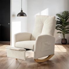 a white rocking chair with a footstool in the middle of a wooden floor