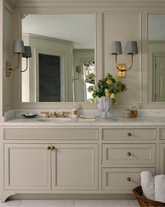 a bathroom with two sinks, mirrors and lights on the wall above them is shown