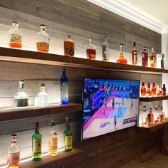 an entertainment center with liquor bottles on the shelves and a flat screen tv in front of it