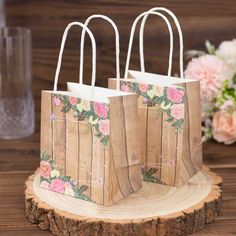 two wooden bags with floral designs on them sitting on a tree stump next to flowers