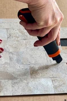 a woman is using a drill to fix a tile floor