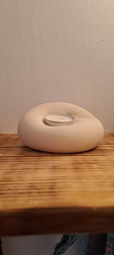 a white object sitting on top of a wooden table next to a lamp and wall