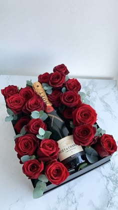 a heart shaped box filled with red roses and a bottle of wine