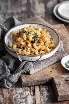 a white bowl filled with macaroni and cheese on top of a wooden table