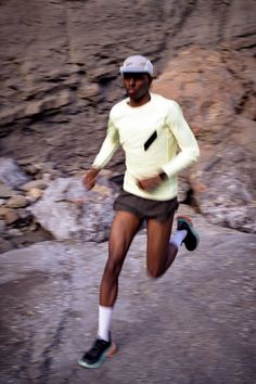 a man running down a rocky path in shorts and a yellow shirt with white socks