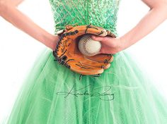 a woman wearing a green dress holding a baseball glove and ball in it's hand