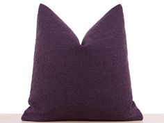 a purple pillow sitting on top of a wooden table next to a black cat statue