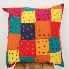 a colorful patchwork pillow sitting on top of a wooden table